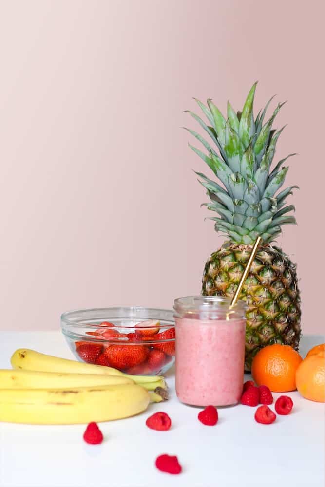 Smoothie glass next to a variety of fruits